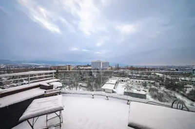a snow covered balcony with a view of a city at Sunny 1BR with Balcony in Sofia