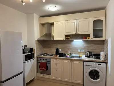 a kitchen with white cabinets and a sink and a refrigerator at Borealis Apartment in Bansko