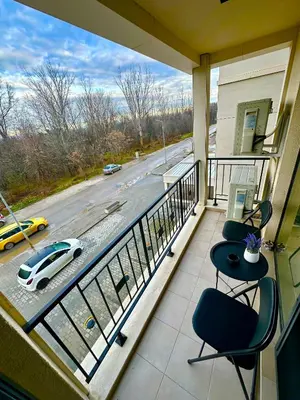 a balcony with two chairs and a car on a street at Regatta Park 1BR Exclusive Suite Parking Included in Plovdiv