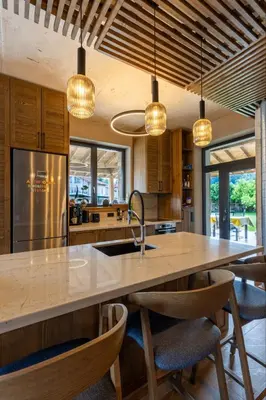a kitchen with a large kitchen island with chairs and lights at Luxurious, modern house in the nature in Belchin in Belchin