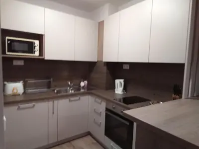 a kitchen with white cabinets and a sink and a microwave at Predela Apartments with Spa in Bansko