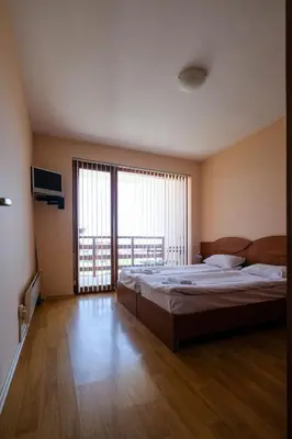 a bedroom with a large bed and a large window at Predela Apartments with Spa in Bansko