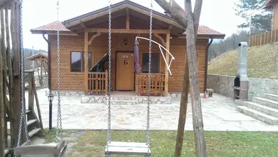 a log cabin with a swing in front of it at Mini Complex Rilski Terasi in Sapareva Banya