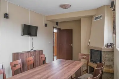 a dining room with a wooden table and a tv at Mini Complex Rilski Terasi in Sapareva Banya
