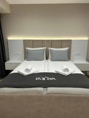 a bed with a black and white blanket and pillows at Резиденция БАЛМОРА in Kalofer