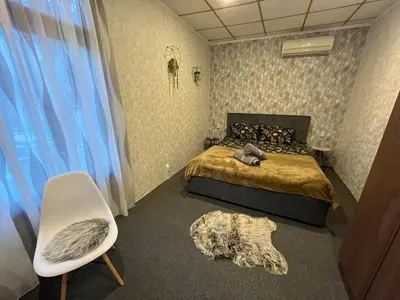 a bedroom with a bed and a white chair and a chair at Delight House in Samokov