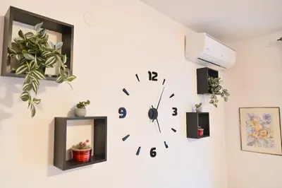 a clock on a white wall with plants on it at The Mountain Hug Studio 1 by SI Stay in Bansko
