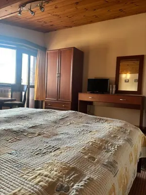 a bedroom with a bed and a desk and a mirror at Kalaydzhiev rooms in Bansko