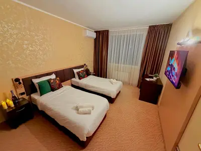 a hotel room with two beds and a tv at Hotel NIRÁ in Sofia