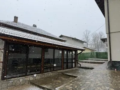 a building covered in snow in a yard at Къща за гости Зорница in Ribarica