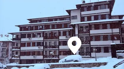 a building covered in snow with a white arrow at SkyCloud Bansko Cozy Modern 1 Min to Gondola in Bansko