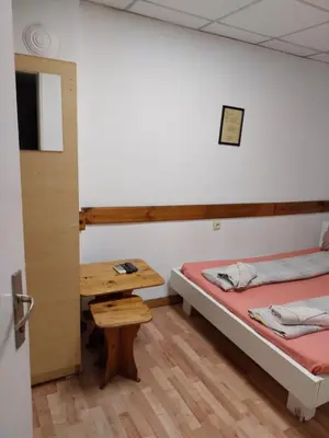 a room with two beds and a wooden table at Скай Румс -3 in Sofia