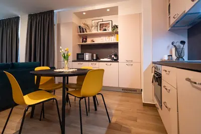 a kitchen and dining room with a table and yellow chairs at Sunny Penthouse with Mountain Views and 180 degrees Terrace in Sofia