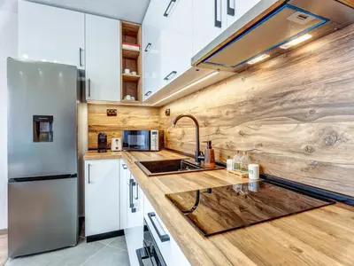 a kitchen with white cabinets and a wooden wall at Stylish 1BR in the Heart of Town in Smolyan