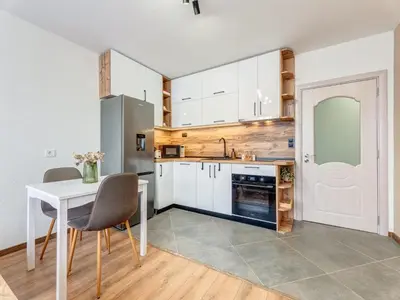 a kitchen with white cabinets and a white table and chairs at Stylish 1BR in the Heart of Town in Smolyan