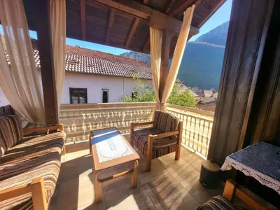 a porch with a couch and a table on a balcony at Къща за гости Йони in Teteven