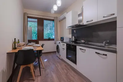 a kitchen with a table and a sink and a stove at Nice 1 BDR apartment next to National Palace of Culture in Sofia