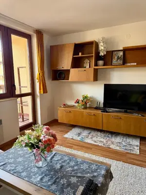 a living room with a table and a tv at Pirin Sense Apartment Home2Host in Bansko