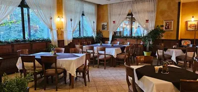 a dining room with tables and chairs and windows at Свети Георги хотел и ресторант in Govedartsi