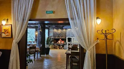 a dining room with a fireplace and a doorway with curtains at Свети Георги хотел и ресторант in Govedartsi