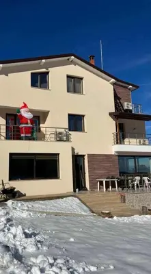 a white house with snow in front of it at Guest House Vanessa 2 in Gulubovo