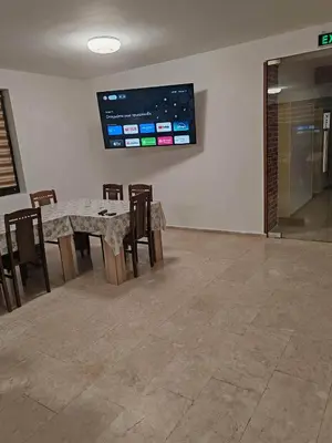a dining room with a table and chairs and a tv at Guest House Vanessa 2 in Gulubovo