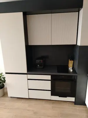 a kitchen with white cabinets and a black counter top at AMur Deluxe Apartment in Sofia