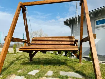 a wooden swing in a park with grass at Къща за гости Касида in Sapareva Banya