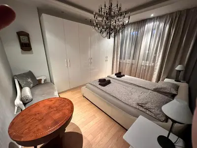 a bedroom with a bed and a table and a chandelier at Bonnie's Stylsih 2BR Home near the Palace in Sofia