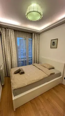 a bed in a bedroom with a large window at Bonnie's Stylsih 2BR Home near the Palace in Sofia
