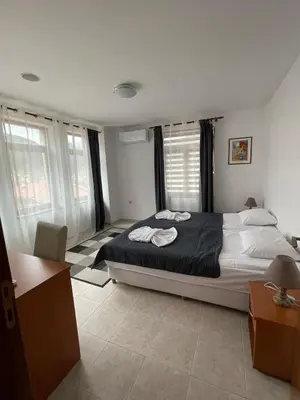 a bedroom with a large bed in a room with windows at Къща за гости Стиляна in Devin