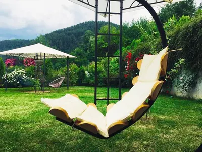 a swing in a yard with chairs and an umbrella at Къща за гости Стиляна in Devin