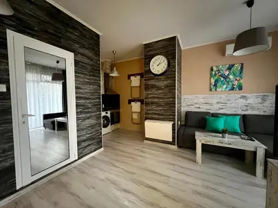 a living room with a couch and a clock on a wall at Flower home 1 in Sofia