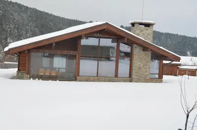 a log cabin with snow on the roof at Gostnici Holiday Home in Razlog