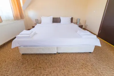 a large bed with white sheets and pillows in a room at Ring Hotel in Blagoevgrad