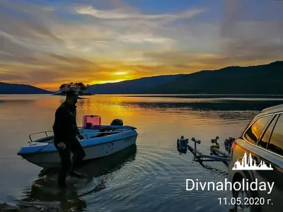a man standing on a boat in the water at Divna Forest & Lake House in Dospat
