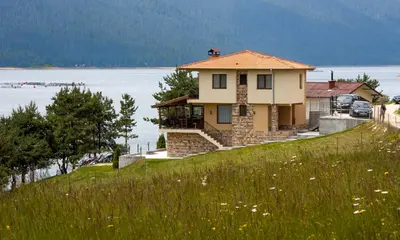 a house on top of a hill with the water at Divna Forest & Lake House in Dospat