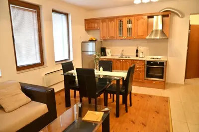 a living room with a table and chairs and a kitchen at Grand Monastery Pamporovo Apartment 5B23 in Pamporovo