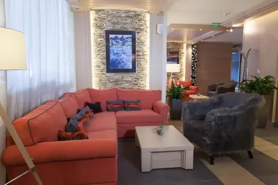 a living room with an orange couch and two chairs at Amira Boutique Hotel in Bansko