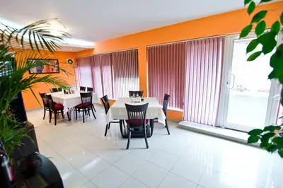 a dining room with white tables and chairs and large windows at Family Hotel Victoria Gold in Mineralni Bani