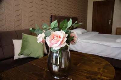 a vase with pink roses sitting on a table at Family Hotel Victoria Gold in Mineralni Bani