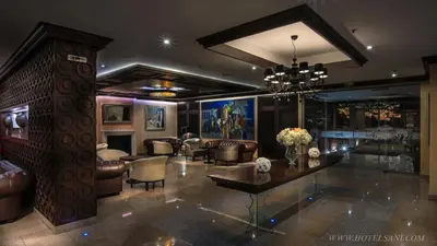 a living room with leather furniture and a chandelier at Hotel Sani in Asenovgrad