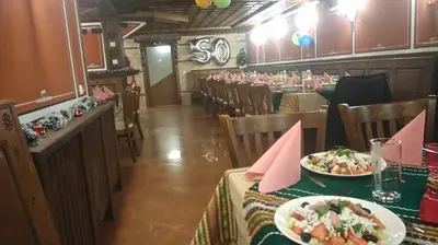 a restaurant with tables and chairs and a plate of food at Guest House H Dzhogolanov in Koprivshtitsa