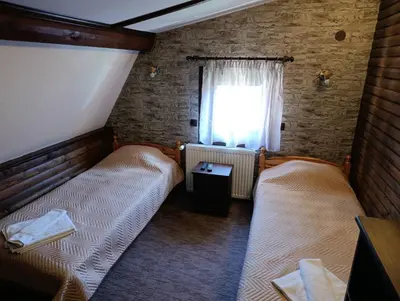 two beds in a small room with a window at Guest House Diva Reka in Beli Iskar