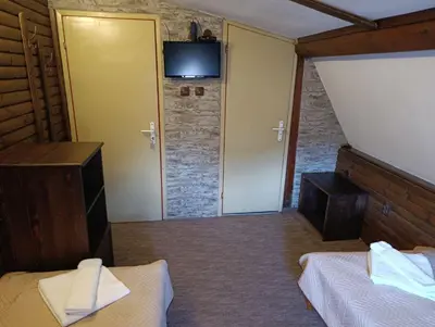 a bedroom with two beds and a television on a wall at Guest House Diva Reka in Beli Iskar