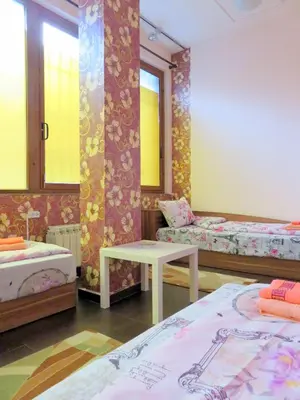 a room with two beds and a table in it at Like Home Guest Rooms in Sofia