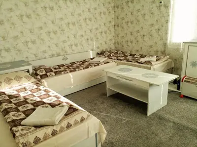 a room with four beds and a table in it at Guest House Emiliya in Ovchartsi