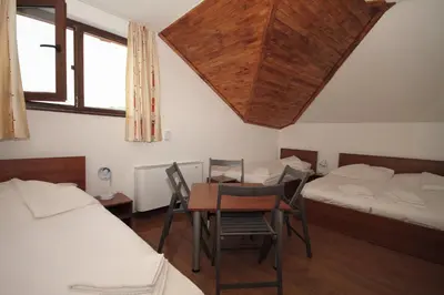 a room with two beds and a table and chairs at Yan BibiYan Guest House in Negushevo