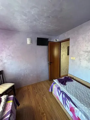 a bedroom with a bed and a tv on the wall at Chepelare Holiday Guest House in Chepelare