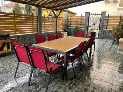 a wooden table with red chairs on a patio at Къща за гости Мегдана in Sopot